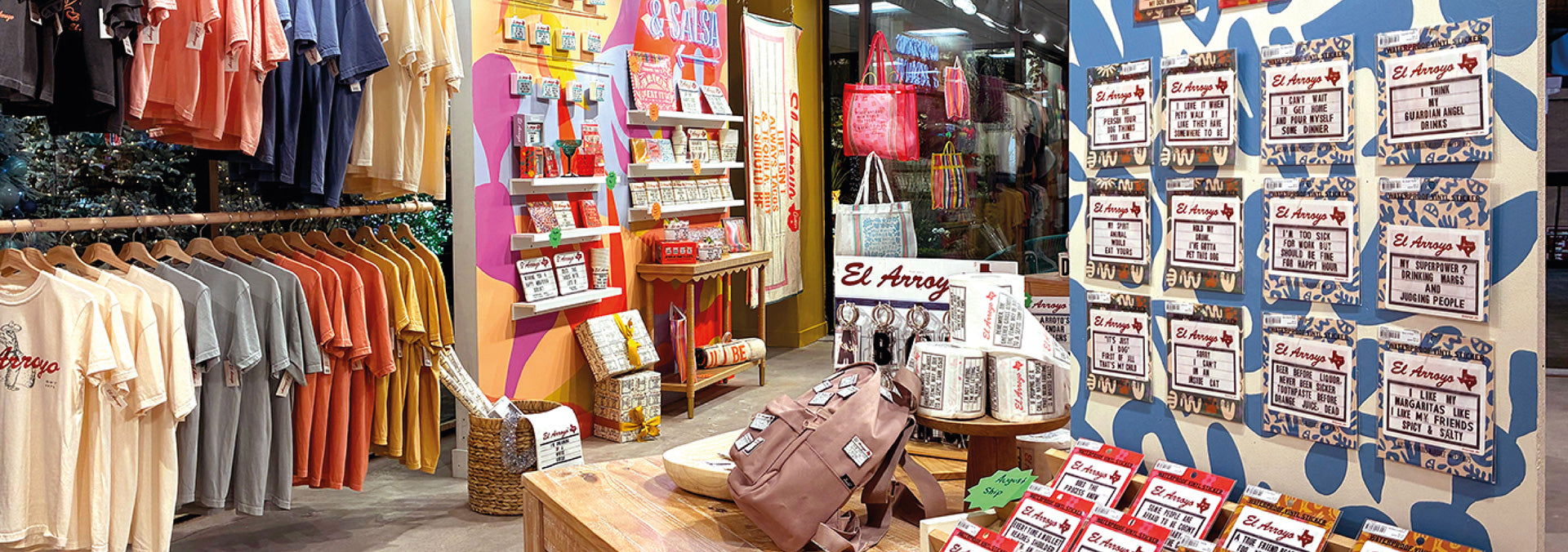 Store interior with clothing racks, a counter, and promotional posters.