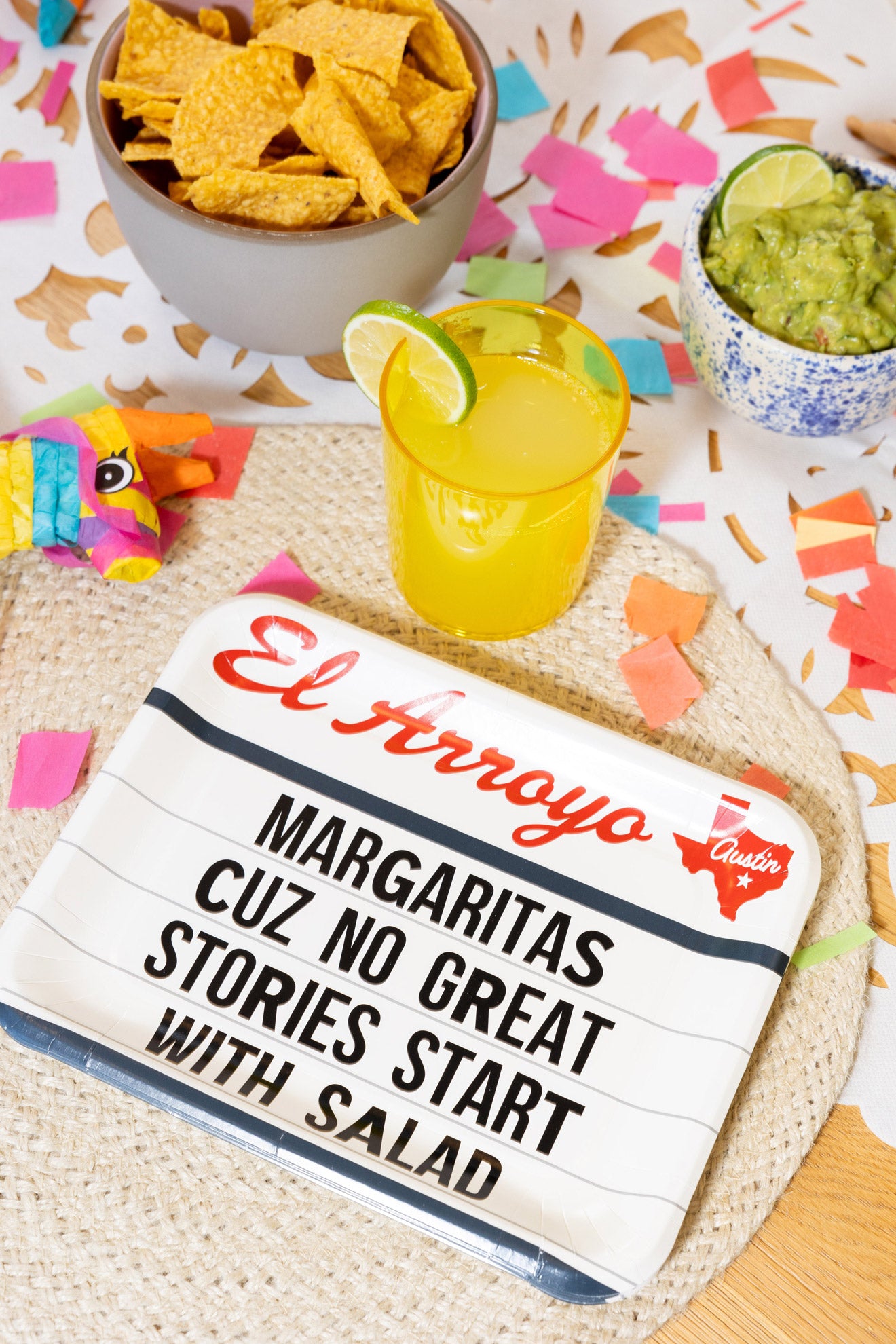 Margarita with lime, tortilla chips, and guacamole on a colorful tablecloth with 'El Arroyo' sign.