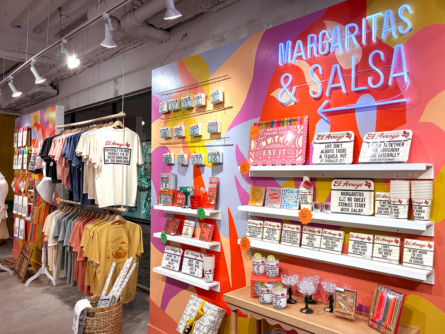 Store interior with clothing racks and product displays, featuring a colorful 'Margaritas & Salsa' sign.